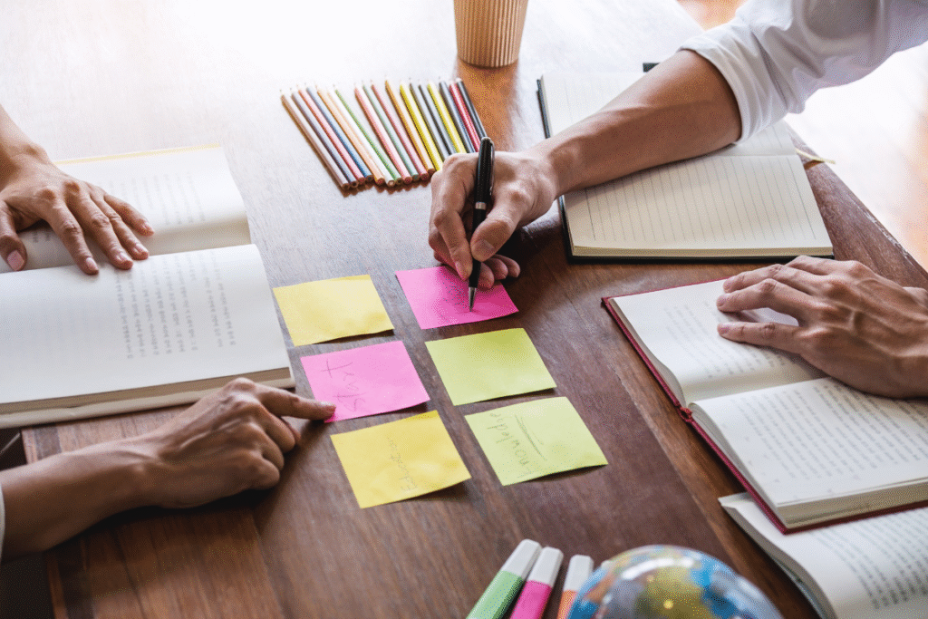 Students planning study tasks using sticky notes, notebooks, and pencils — representing organisation and overcoming procrastination.